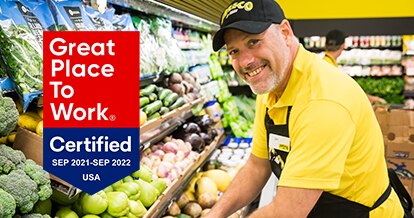 'Great Place to Work - Certified Sep 2021-Sep 2022' - Fresco Y Mas associate smiling and stocking produce