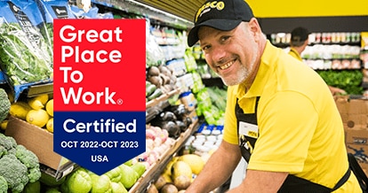 'Great Place to Work - Certified Oct 2022-Oct 2023' - Fresco Y Mas associate smiling and stocking produce