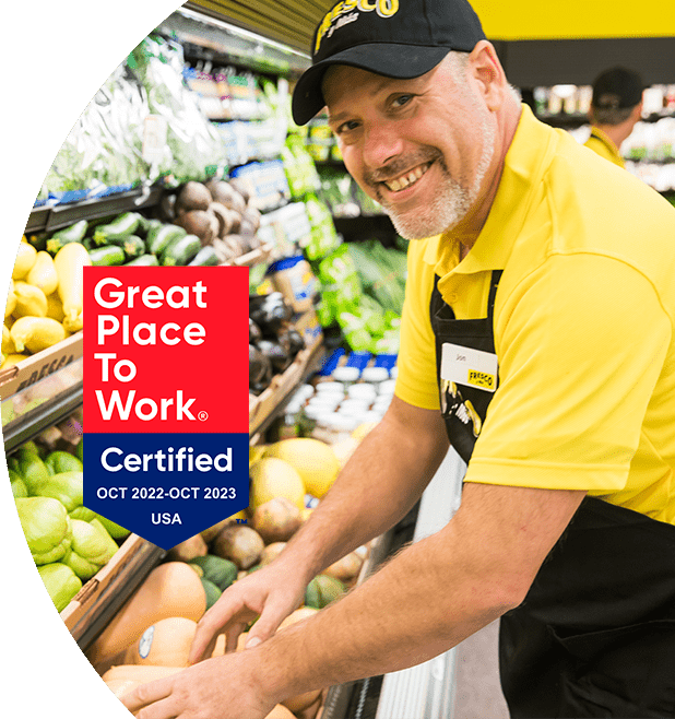 'Great Place to Work - Certified Oct 2022-Oct 2023' - Fresco Y Mas associate smiling and stocking produce