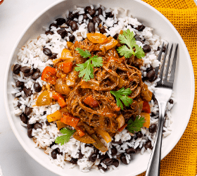 Flank steak ropa vieja with rice and beans on a plate