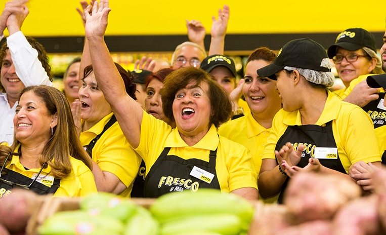 Group of Fresco Y Mas associates smiling and cheering with their hands up